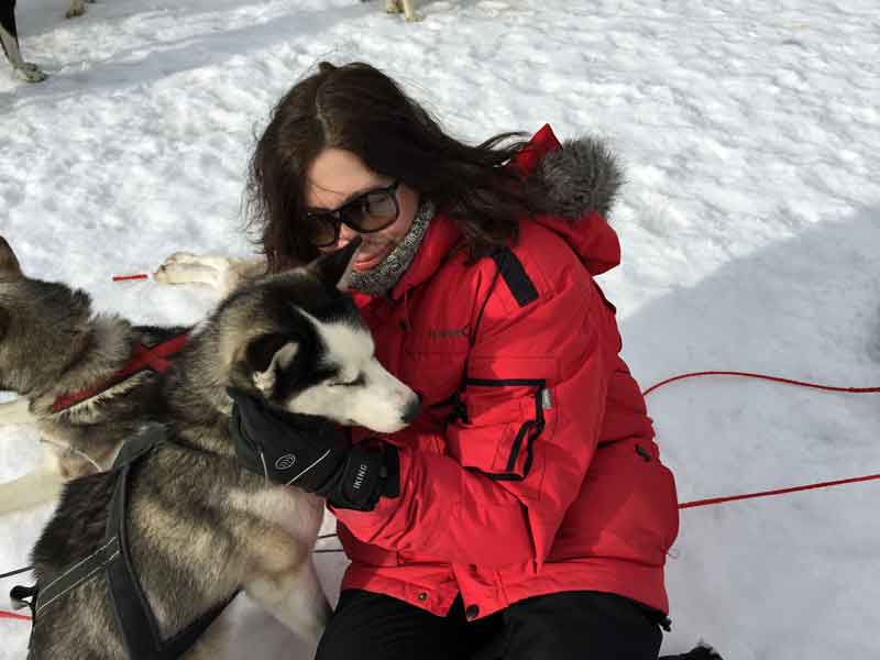 Karin is cuddling a sled dog. 