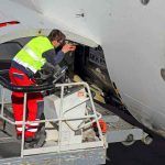 Airplane technician servicing a cargo hatch on a jet.