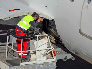 Airplane technician servicing a cargo hatch on a jet.