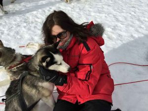 Karin is cuddling a sled dog.