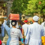 Couple going to temple with offerings in Bali, Indonesia.